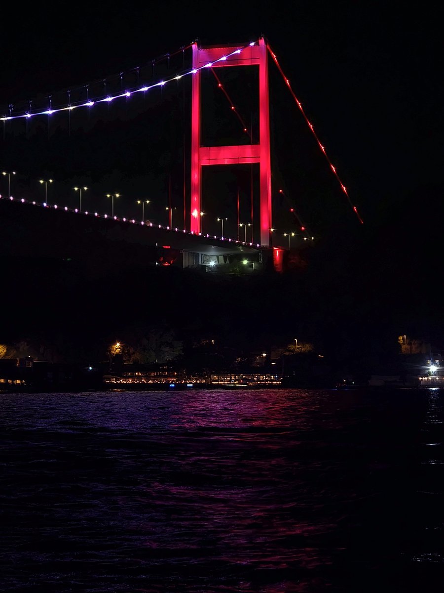 Gece kırmızı ışıklarla aydınlatılmış asma köprü ayağı ve altında Boğaz